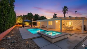 Una casa moderna con piscina, mobiliario exterior y un patio cubierto.
