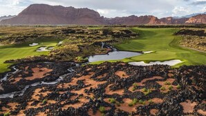 A golf course with a rocky foreground, a pond, and mountains in the background. - Red Rock Haven at Terra Resort | Sage Vacations (Hurricane)
