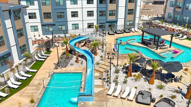 A hotel with a pool area featuring a water slide, lounge chairs, and a covered seating area. - Red Rock Haven at Terra Resort | Sage Vacations (Hurricane)
