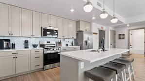 A modern kitchen with a central island, stainless steel appliances, and pendant lighting. - Red Rock Haven at Terra Resort | Sage Vacations (Hurricane)
