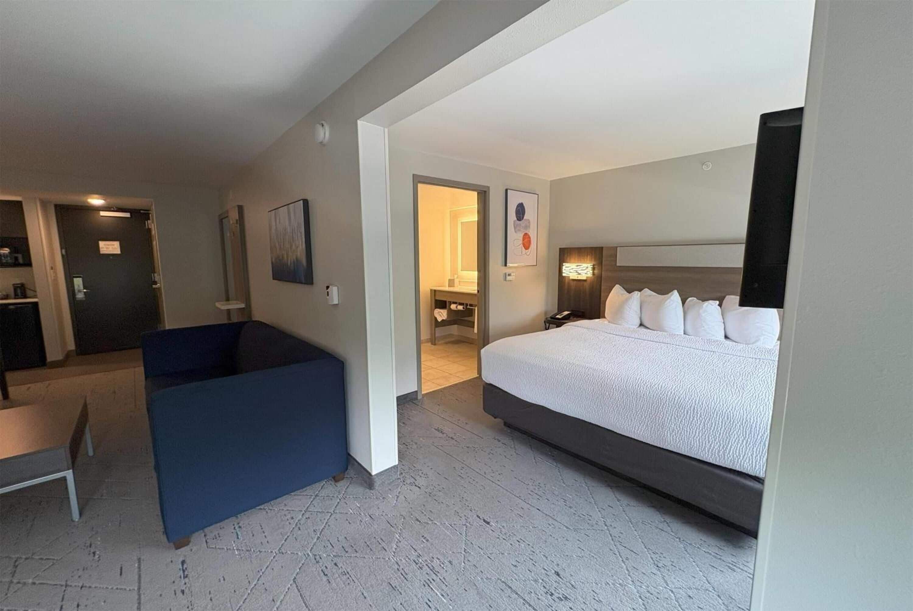 A hotel room with a large bed, a desk, and a seating area.