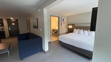 A hotel room with a large bed, a desk, and a seating area.