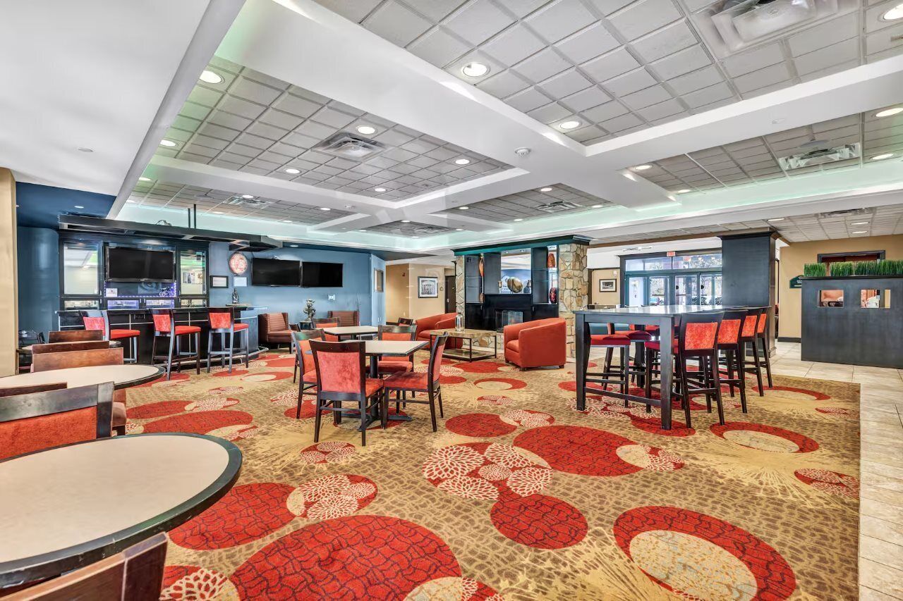 A hotel lobby with multiple seating areas, a reception desk, and a television screen.