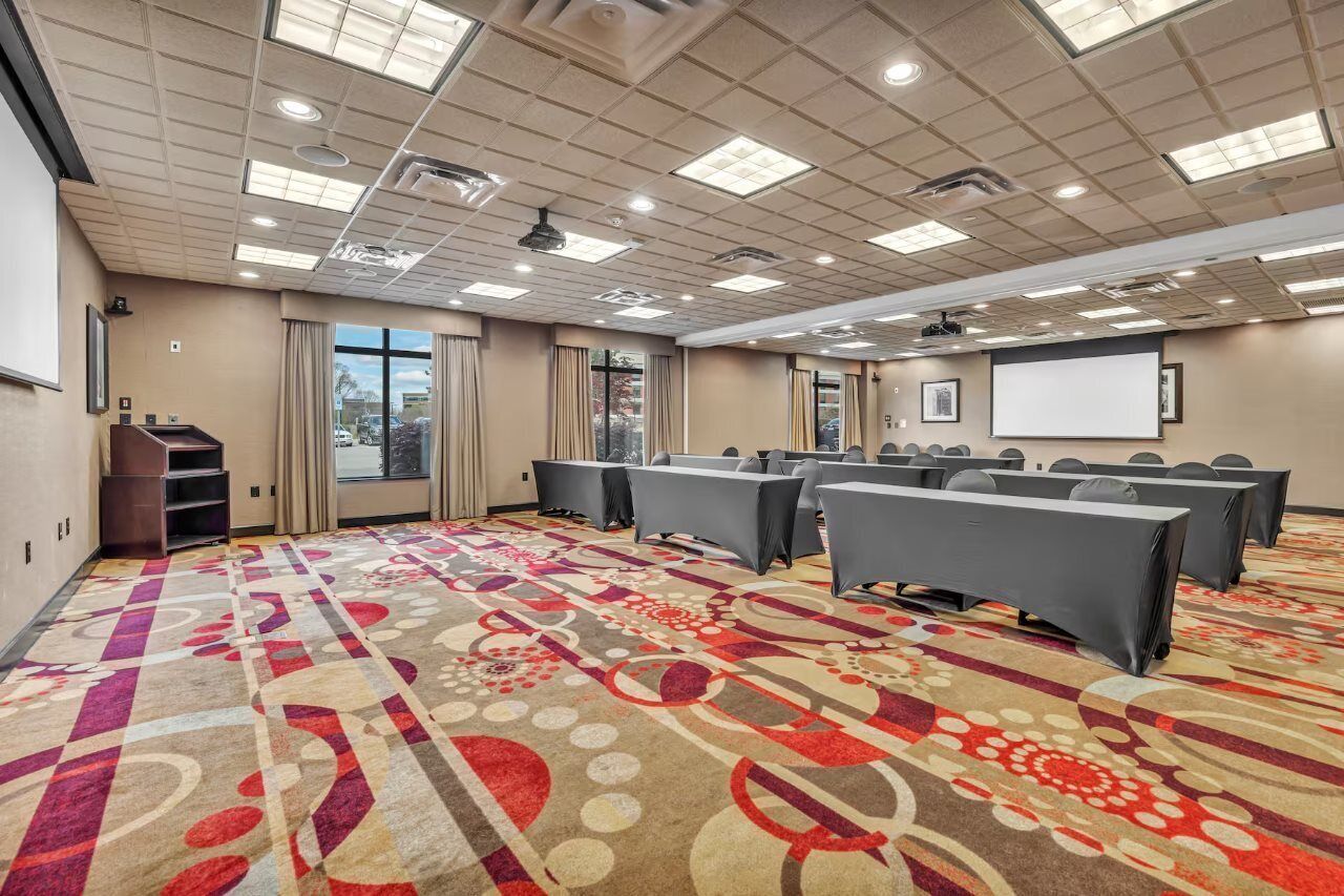 A conference room with a carpeted floor, a projector screen, and a presentation podium.