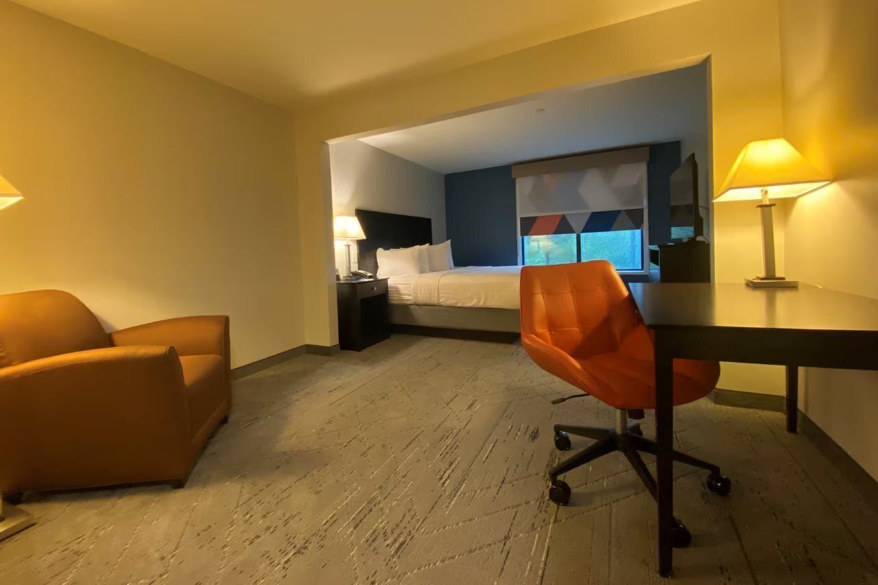 Una habitación de hotel con cama, escritorio, silla y mesita de noche.