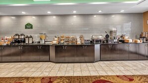 A breakfast bar with a variety of food items and a coffee station. - Holiday Inn Express & Suites RALEIGH WEST - LENOVO CENTER by IHG (Meredith)