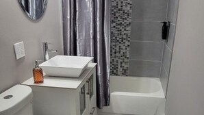 A modern bathroom with a white sink, toilet, and bathtub.