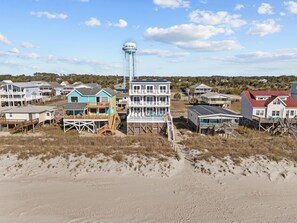A beachfront property with a water tower, multiple houses, and a sandy beach. - Clear Skies: Spacious 7-Bedroom Oceanfront Retreat in Oak Island, NC, perfect for up to 20 guests. (Oak Island)