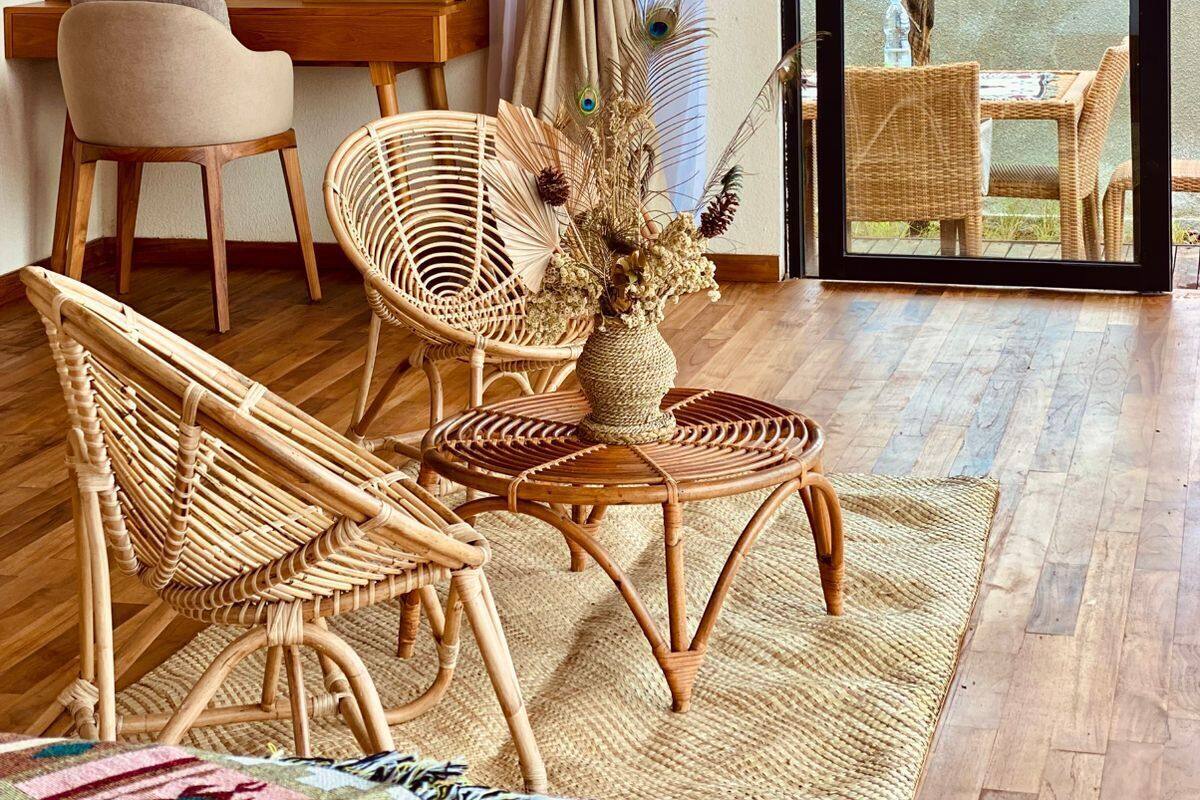 Una habitación con muebles de mimbre, una cortina, una obra de arte en la pared y vistas a través de un ventanal.