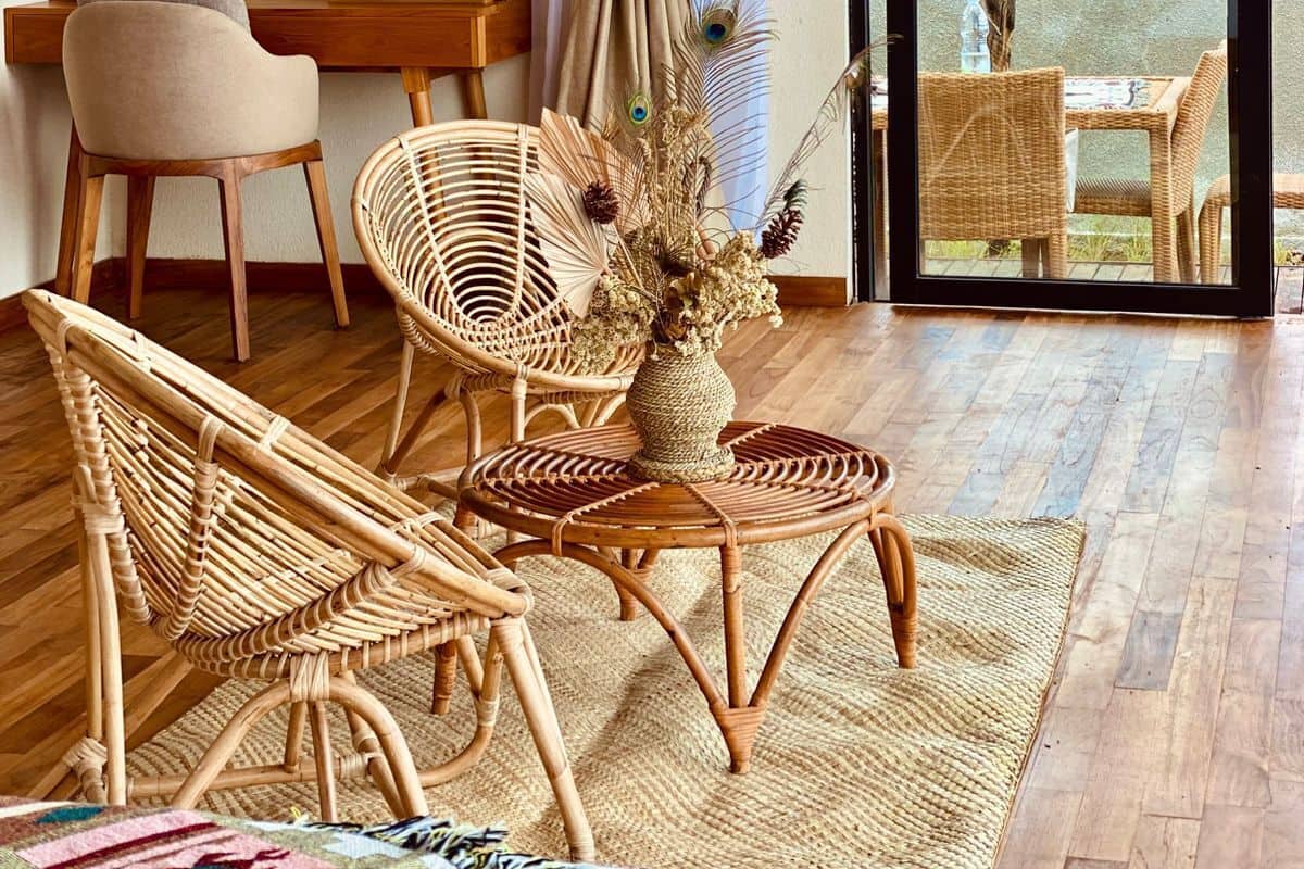 Una habitación con muebles de mimbre, una cortina, una obra de arte en la pared y vistas a través de un ventanal.