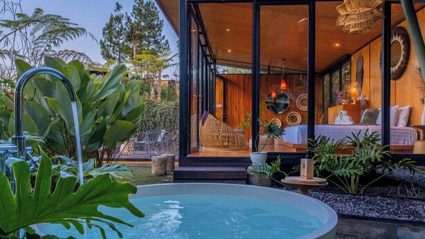 A modern house with a swimming pool, a wooden deck, and a glass-enclosed bedroom with a bed and a sofa. - Black Lava Camp Kintamani (Kintamani)