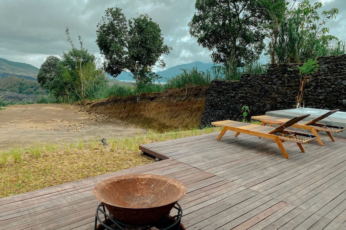 Una terraza de madera con sillones de descanso y un cuenco grande, con vistas a un paisaje montañoso.