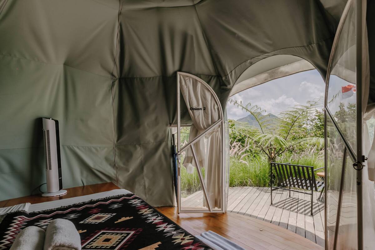 Una carpa con cama, calentador y vista a la vegetación.