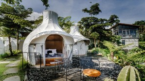 A tented accommodation with a bed, seating area, and a view of the surrounding greenery. - Black Lava Camp Kintamani (Kintamani)
