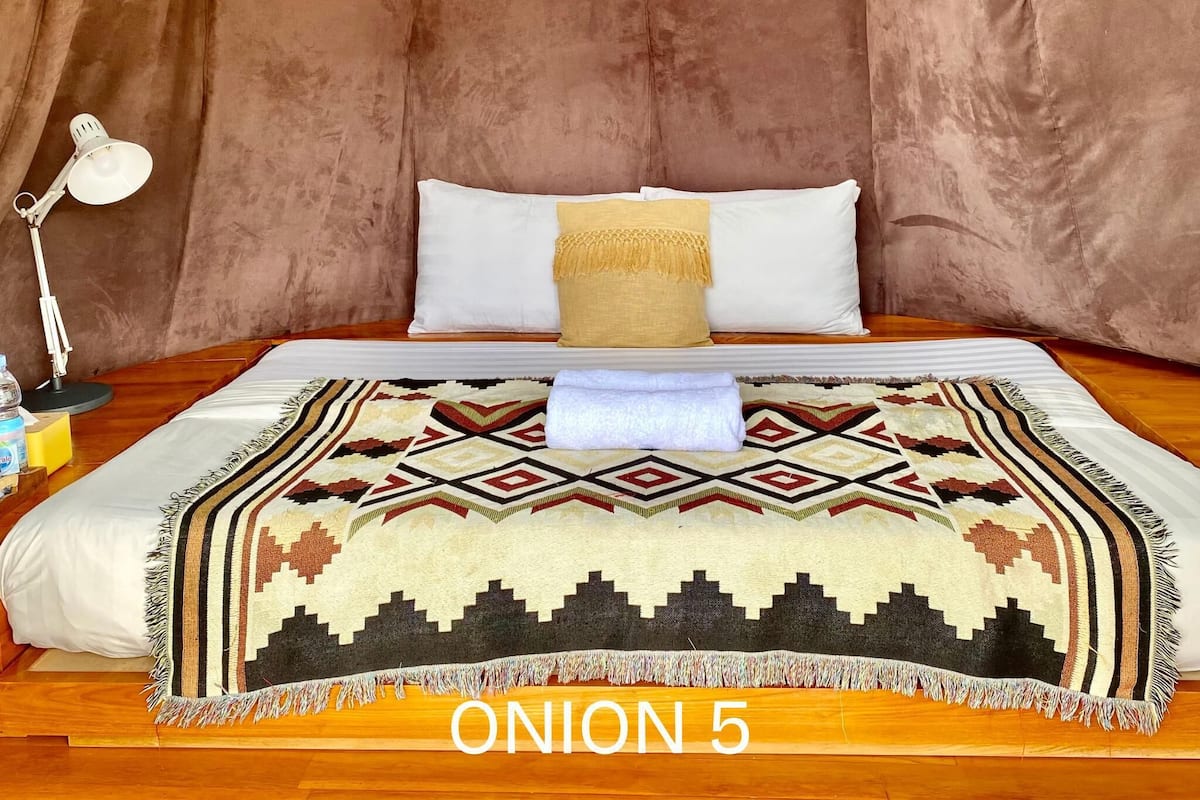 Una habitación con una cama, una lámpara y una manta.