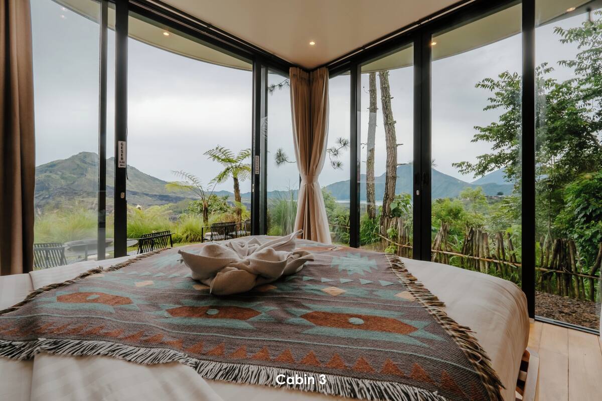 Un dormitorio con una cama grande, un tapete estampado y vistas a zonas verdes y montañas.