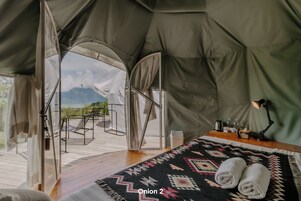 Una tienda de campaña con cama, ventana y vistas a las montañas.