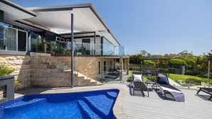 Ett modernt hus med en swimmingpool, utemöbler och en trappa i sten.