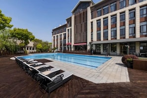 Un hôtel moderne doté d’une piscine, d’un espace détente et d’un bâtiment à plusieurs étages avec de grandes fenêtres.