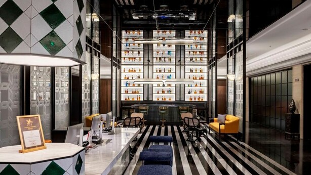Een moderne lobby met een receptiebalie, een zithoek en een grote displaywand.