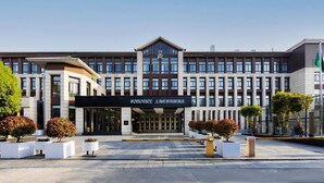 Een modern hotel met een symmetrische gevel, grote toegang deuren en een opvallend bord.