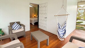 Una habitación amplia con muebles de mimbre, una silla colgante y un ventilador de techo.