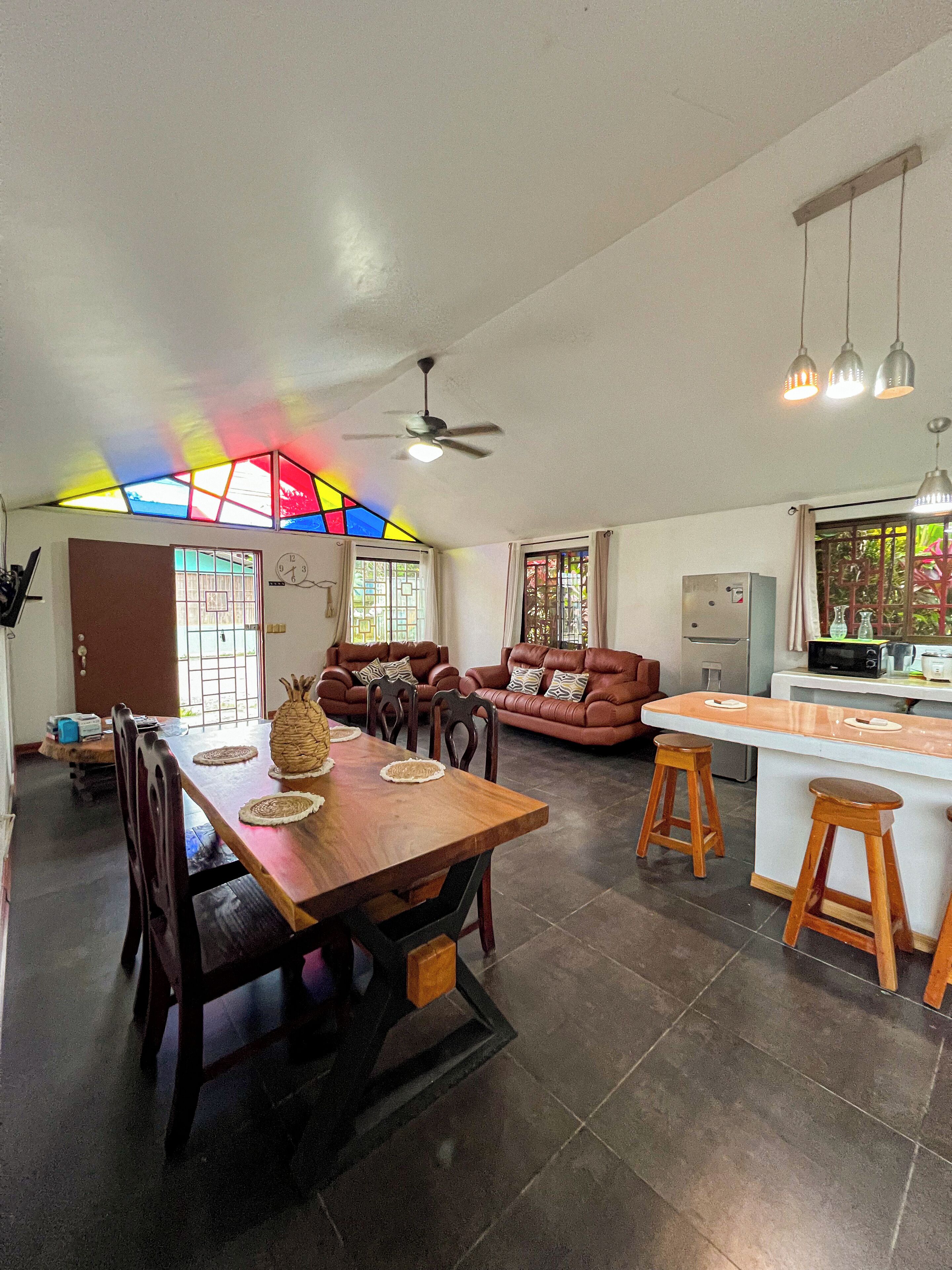 A spacious living area with a dining table, sofas, and a kitchen area.