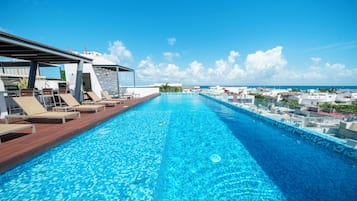 Alberca al aire libre, sombrillas en la alberca y camastros