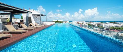 Alberca al aire libre, sombrillas en la alberca y camastros