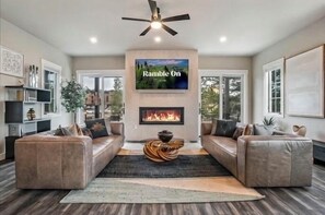 A modern living room with a fireplace, leather sofas, a flat-screen TV, and a ceiling fan. - Home Spa Retreat Downtown WP: Rooftop Hot Tub + Sauna - Walk to Shops & Shuttle (Winter Park)