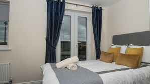 Quarto com cama, janela e cortinas.