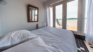 A bedroom with a large bed, a window with a view of the outdoors, and a radiator on the wall.