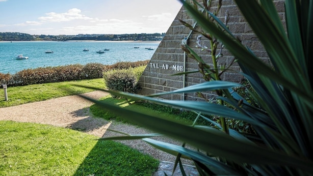 A stone building with a view of the sea and boats.