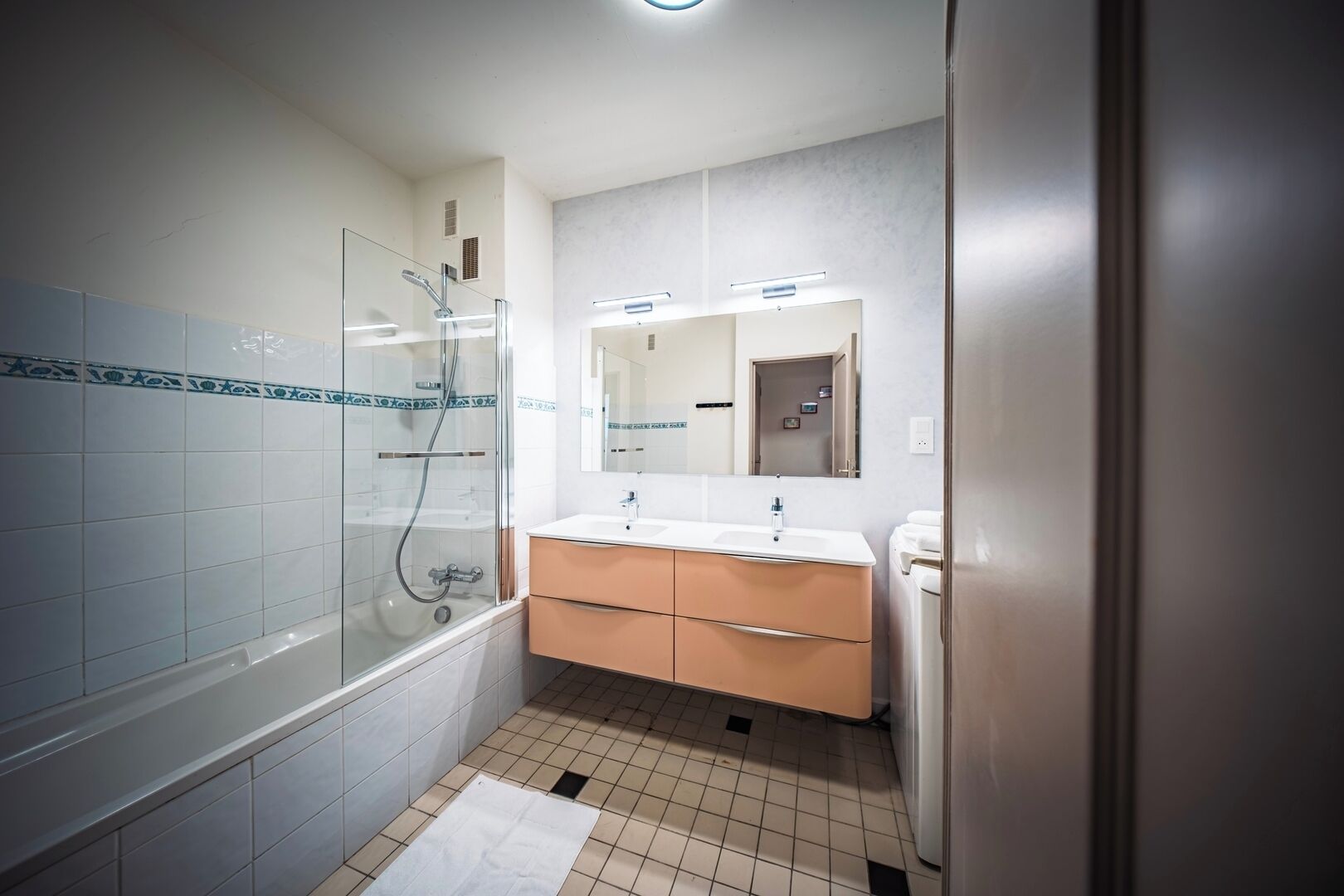 A bathroom with a glass shower enclosure, a sink with a mirror, and a towel rack.