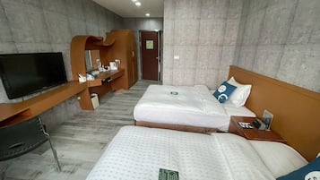 A hotel room with two beds, a TV, a desk, and a bathroom.