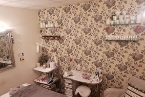 A room with a floral wallpaper, a mirror, a vanity with shelves, and a bed. - Holiday Inn COLCHESTER by IHG (Eight Ash Green)