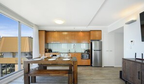 Eine moderne Küche mit Holzschränken, Edelstahlgeräten und einem Essbereich mit einem Holztisch, gedeckt für vier Personen.