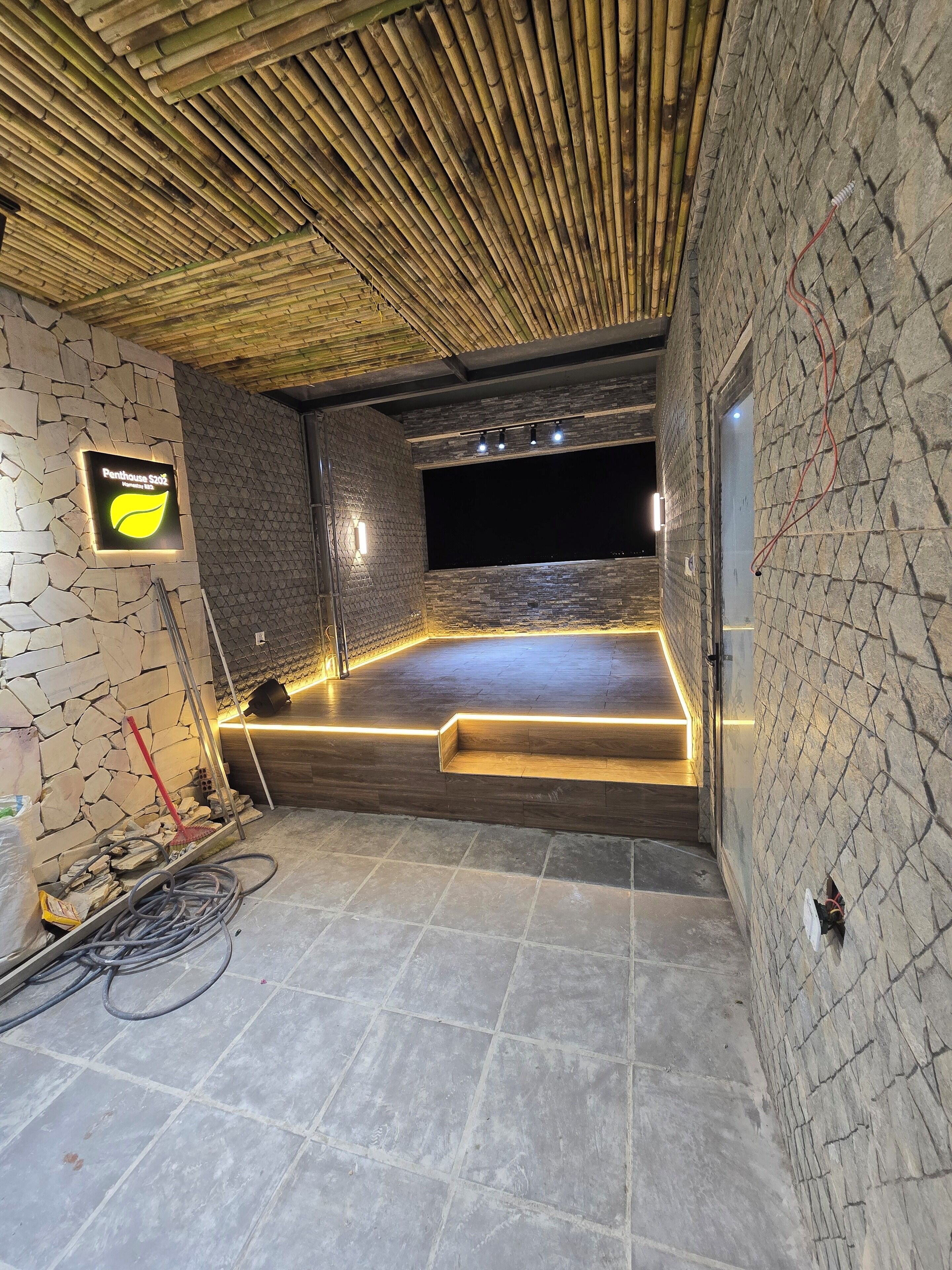 A modern interior with a stone wall, a bamboo ceiling, and a sign indicating a restaurant.