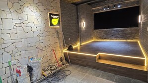Een kamer met een stenen muur, een bamboe plafond en een podium met LED-verlichting.