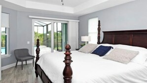 A modern bedroom with a large bed, a chair, and a view of the outdoors through a glass door. - Phoenix, quite Area, Pool and great water few (Cape Coral)