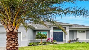 A modern two-story house with a well-maintained lawn, a palm tree, and a garage. - Phoenix, quite Area, Pool and great water few (Cape Coral)