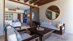 Un soggiorno moderno con un grande specchio, travi in legno a soffitto e un’accogliente zona relax con divano e tavolino.