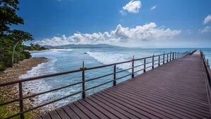 Una passerella in legno che conduce a una spiaggia, con le onde che si infrangono sulla riva.