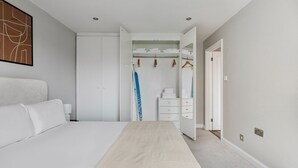 Ein modernes Schlafzimmer mit einem großen Bett, einem begehbaren Kleiderschrank und einem Badezimmer mit Handtuchhalter.
