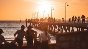 Eine Pier mit Menschen, die während des Sonnenuntergangs darauf entlanggehen.