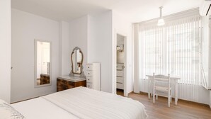 Un dormitorio con cama, cómoda, espejo, escritorio y silla.