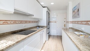Una cocina moderna con armarios blancos, encimeras de granito y suelo de madera.