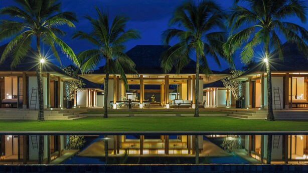 Un moderno resort con piscina, palmeras y un espacio exterior bien iluminado.