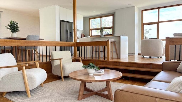 Un salon moderne avec un banc en bois, une table basse ronde et un canapé.