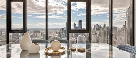 A glass-top table with decorative items and a cityscape view through large windows.